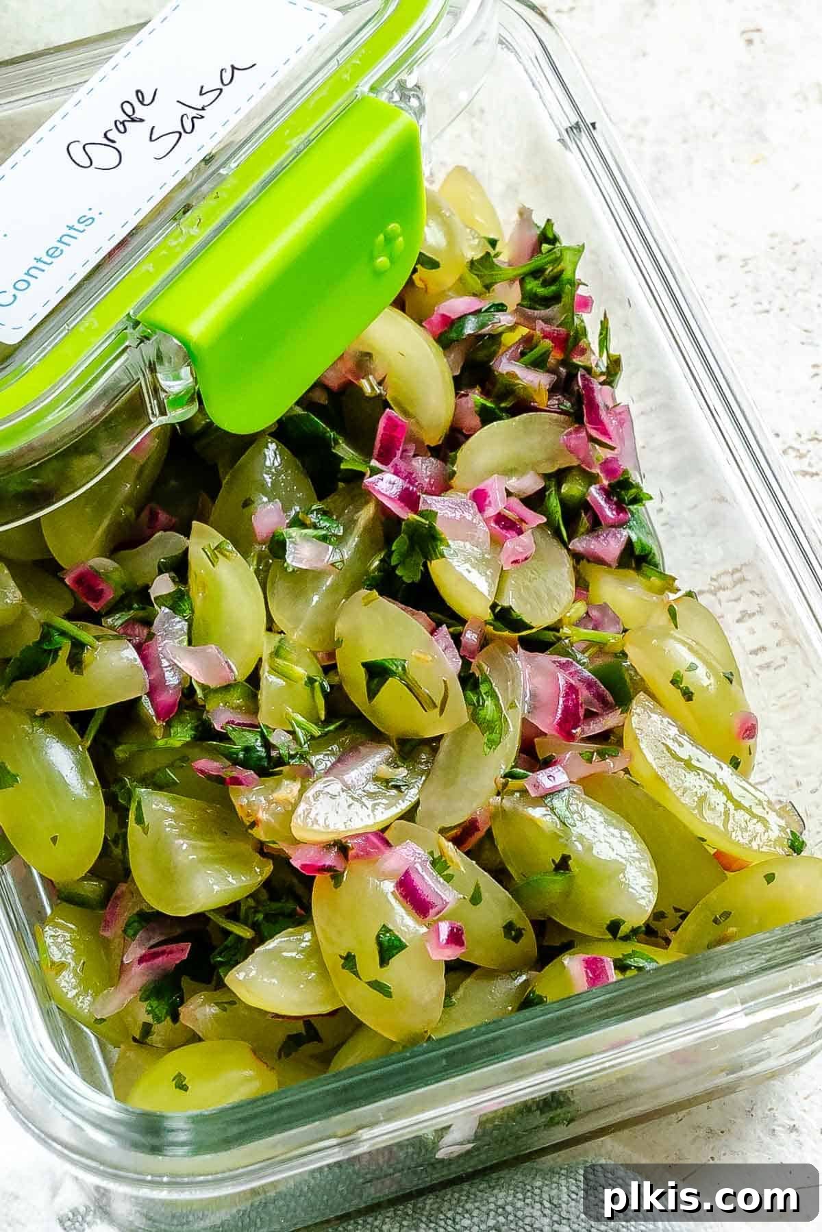 Completed Fresh Grape Salsa stored in a clear airtight container in the refrigerator, ready for later consumption.