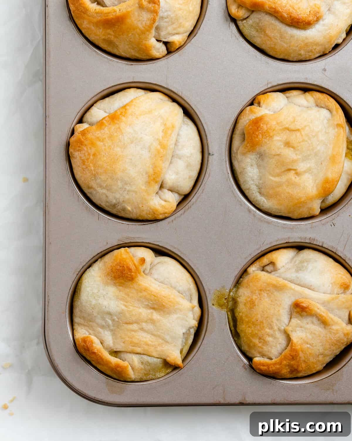 A close-up shot of several Mini Vegan Pot Pies stacked, revealing their flaky crust and golden-brown perfection, with a focus on their appealing texture.