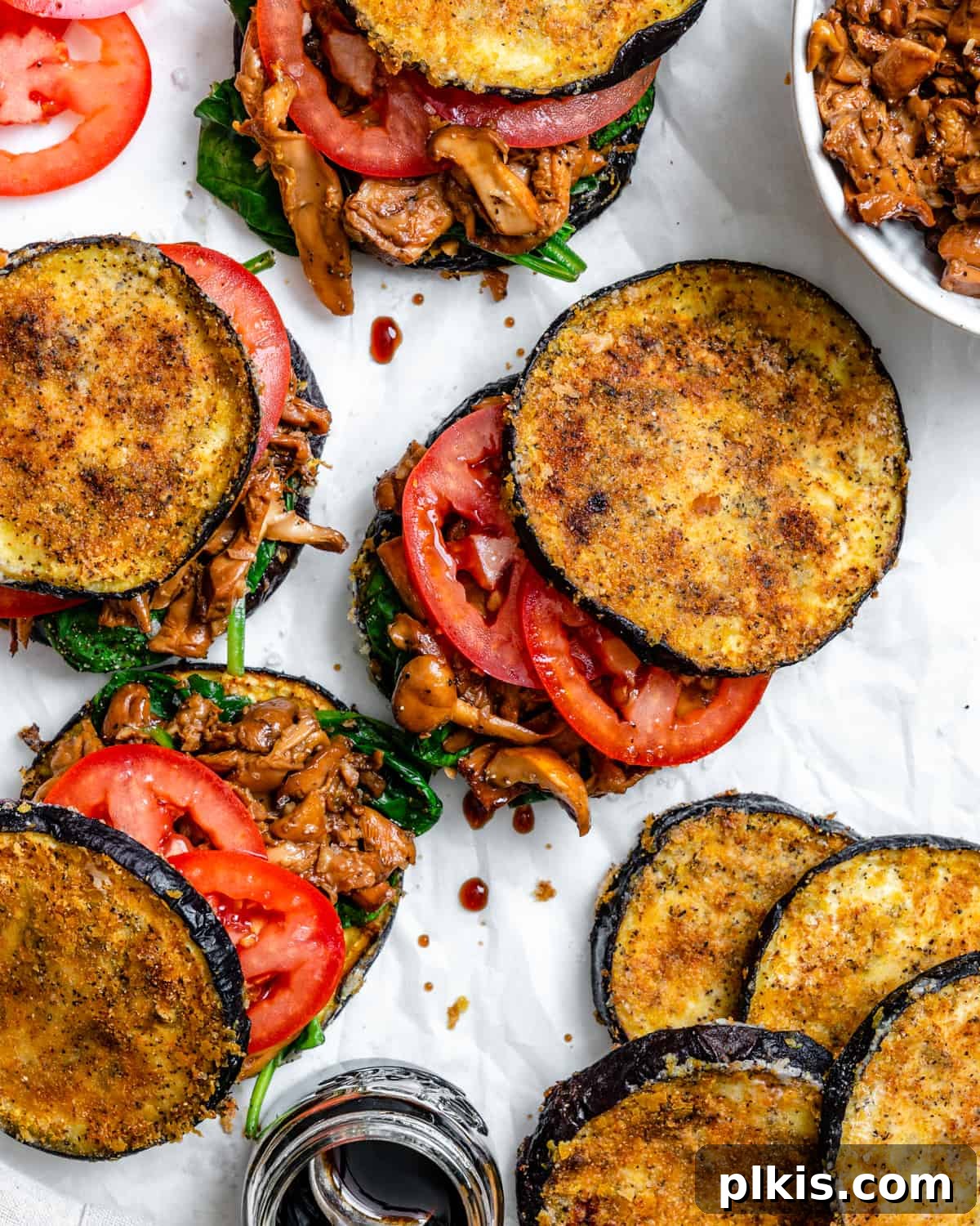 Two Tantalizing Eggplant Stacks 2 Beautifully arranged Eggplant Stacks with colorful vegetable layers on a white surface, inviting and fresh.