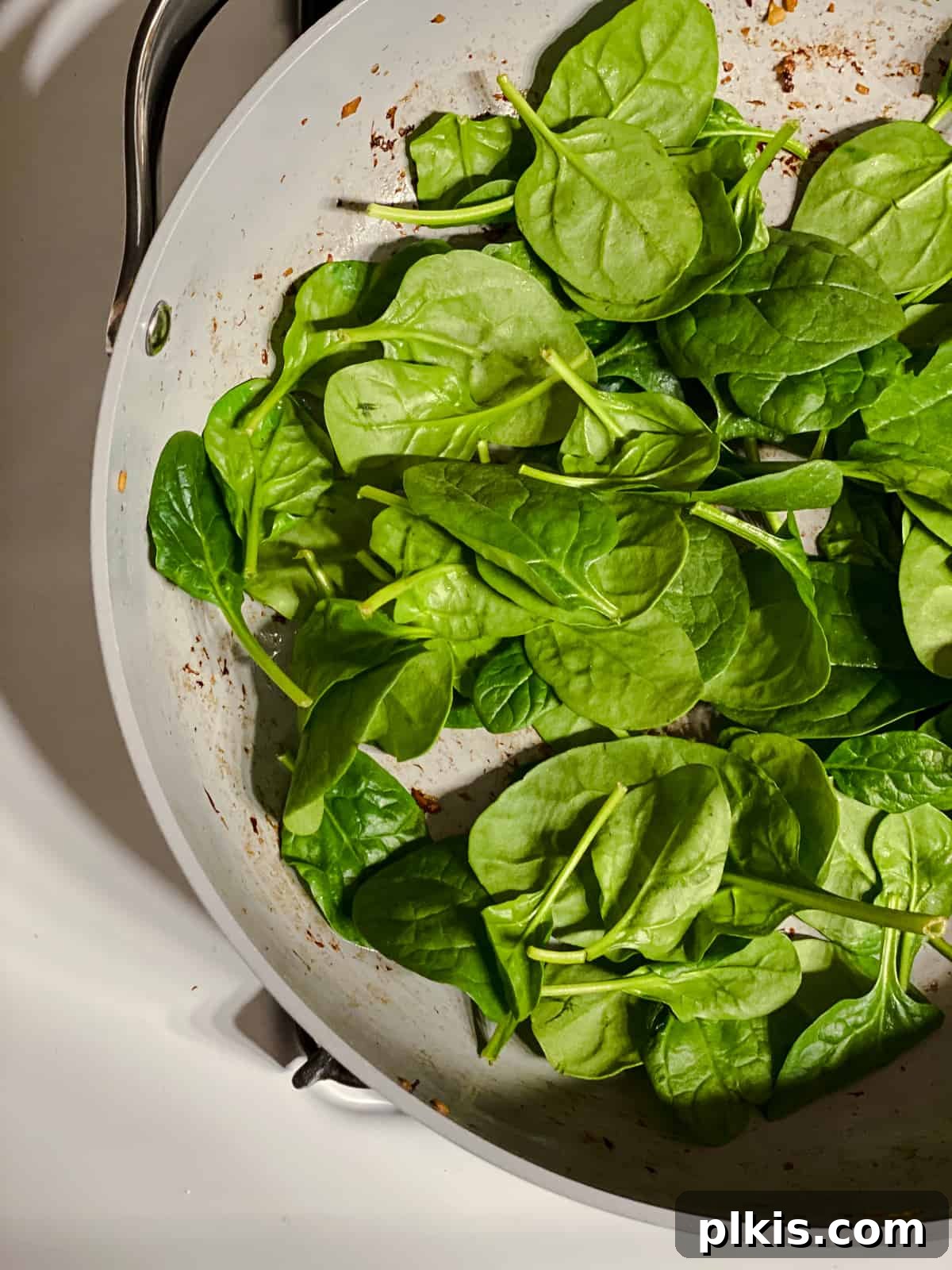 Two Tantalizing Eggplant Stacks 11 Fresh spinach being added to a hot pan, ready to be wilted for the eggplant stacks.