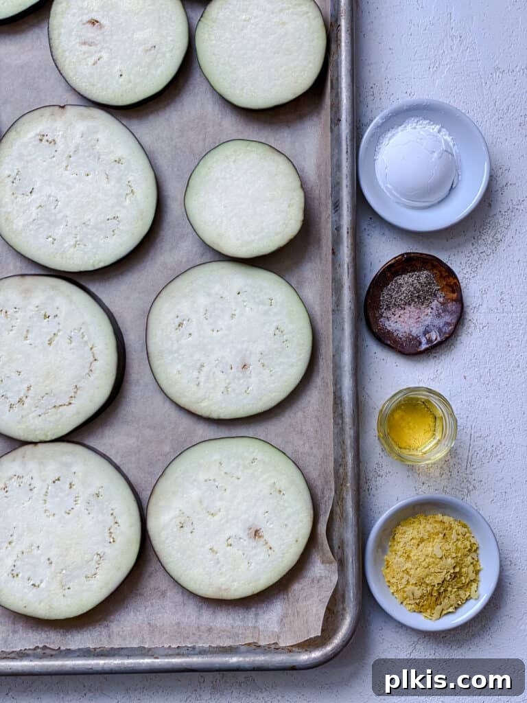 Two Tantalizing Eggplant Stacks 5 Eggplant slices laid out on a baking tray, accompanied by measured seasonings like nutritional yeast and starch, ready for coating.