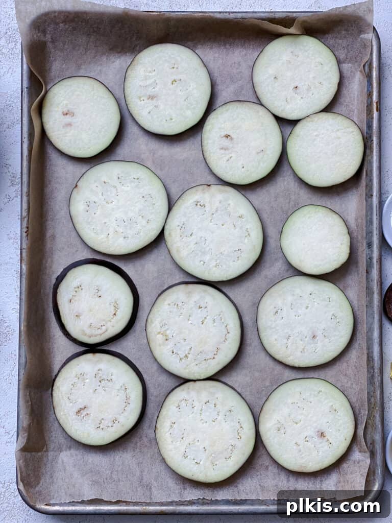Two Tantalizing Eggplant Stacks 6 A baking tray filled with eggplant slices, lightly oiled and seasoned, spread evenly for baking.