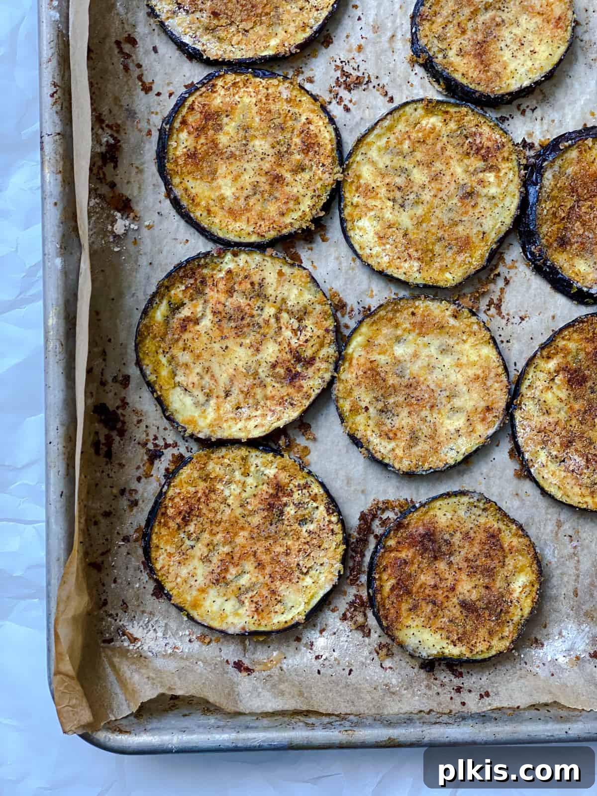 Two Tantalizing Eggplant Stacks 8 Baked eggplant slices, golden and tender, cooling on a baking tray after being removed from the oven.