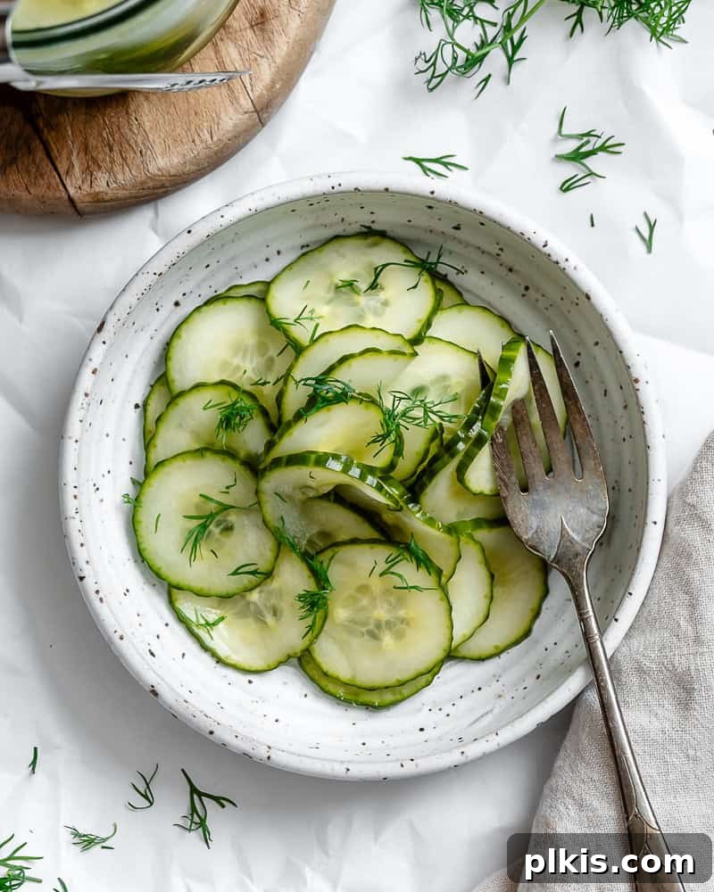 Crisp Cucumber Dill Delight 2 Freshly prepared cucumber dill salad in a white bowl with a fork, ready to be enjoyed.