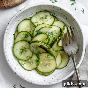 Crisp Cucumber Dill Delight 12 cucumber dill salad in a white bowl with a fork.