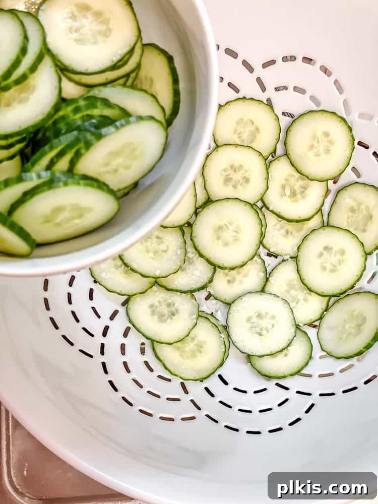 Crisp Cucumber Dill Delight 4 Thinly sliced cucumbers placed in a white colander, ready for draining.