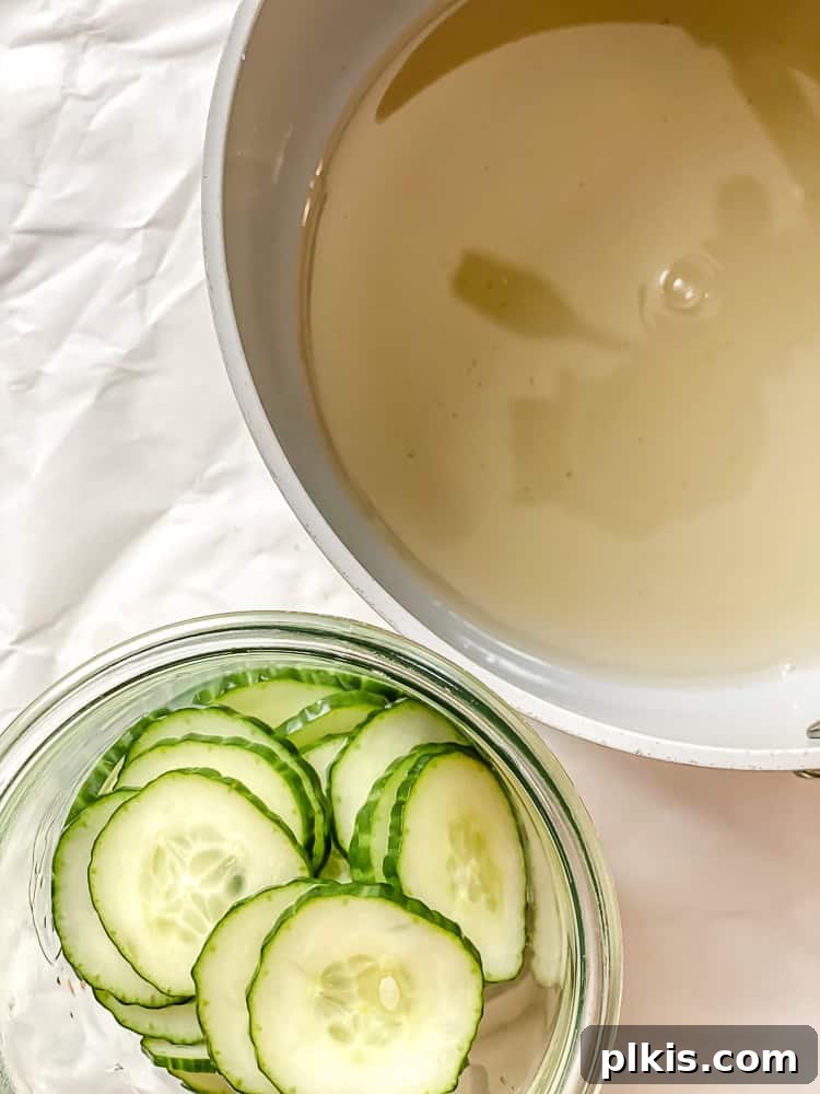 Crisp Cucumber Dill Delight 7 Rinsed and dried cucumber slices arranged in a clear glass dish, ready for marination, with the cooling marinade in the background.