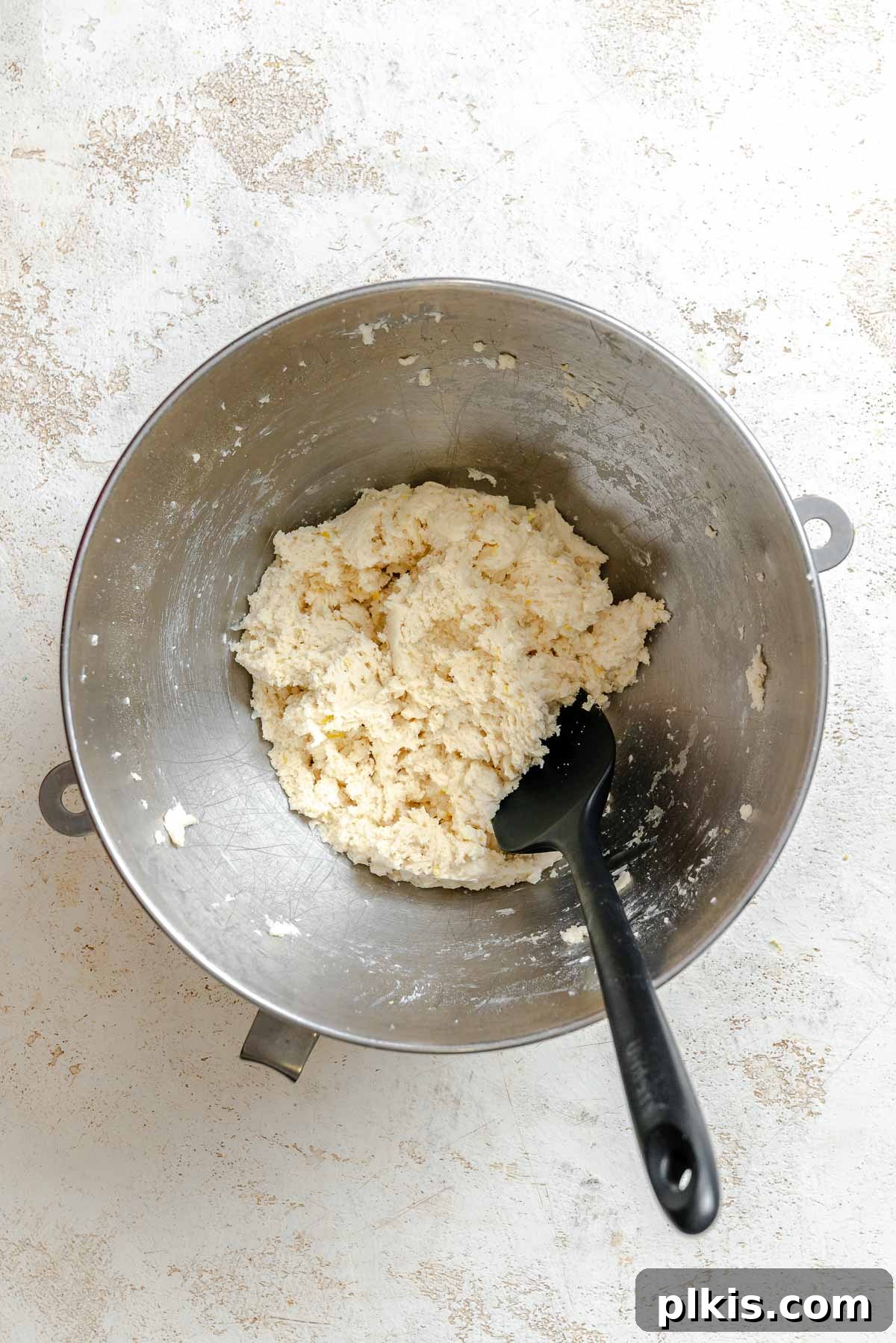 Tangy Lemon Crinkle Delights 6 The process of combining wet and dry ingredients in a mixing bowl to form a cohesive cookie dough.