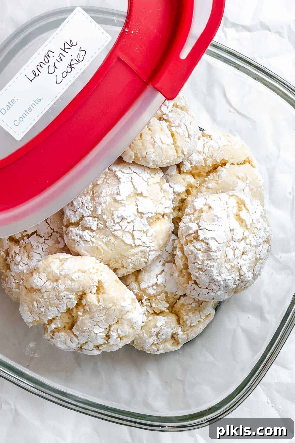 Tangy Lemon Crinkle Delights 10 Freshly baked lemon crinkle cookies neatly stacked inside an airtight storage container, ready for preservation.