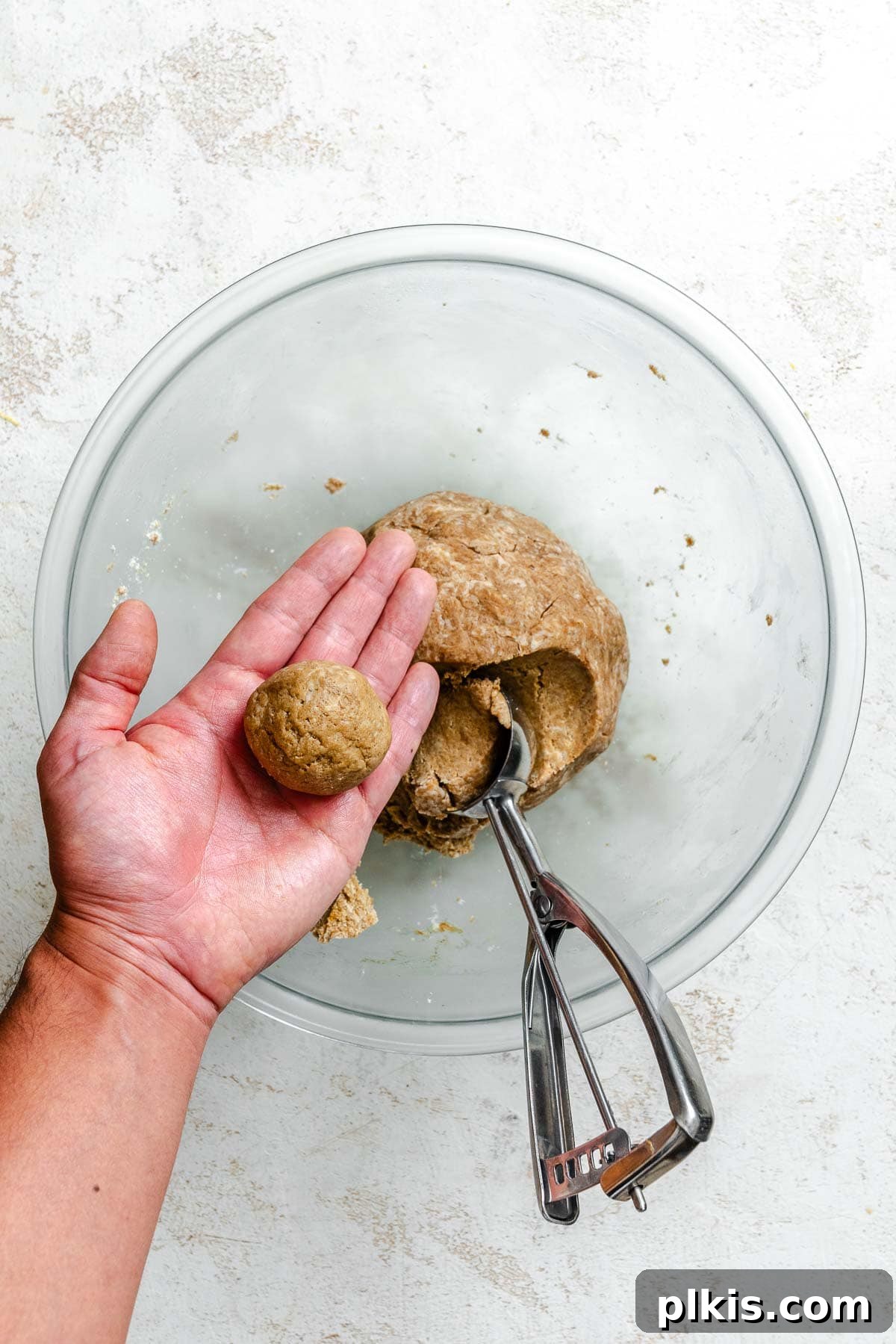 Festive Eggless Gingerbread Crinkle Cookies 7 Process shot showing gingerbread cookie dough shaped into a ball and covered with plastic wrap, ready for chilling.