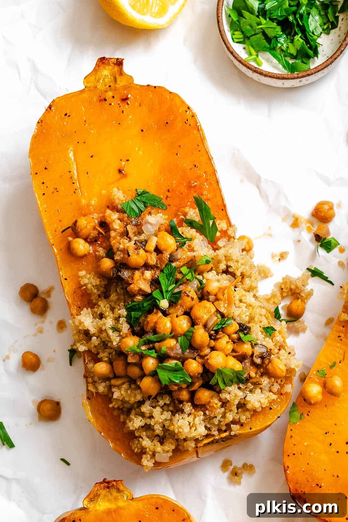 Wholesome Vegan Butternut Squash Boats 2 Completed Vegan Stuffed Butternut Squash on a white surface, garnished with fresh herbs.
