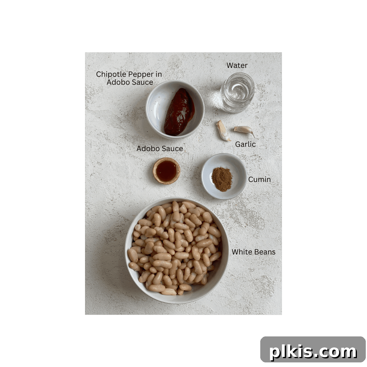 Smoky Chipotle White Bean Dip 3 ingredients for Chipotle White Bean Dip measured out against a white surface, including canned beans, chipotle peppers, garlic, lime, and cumin