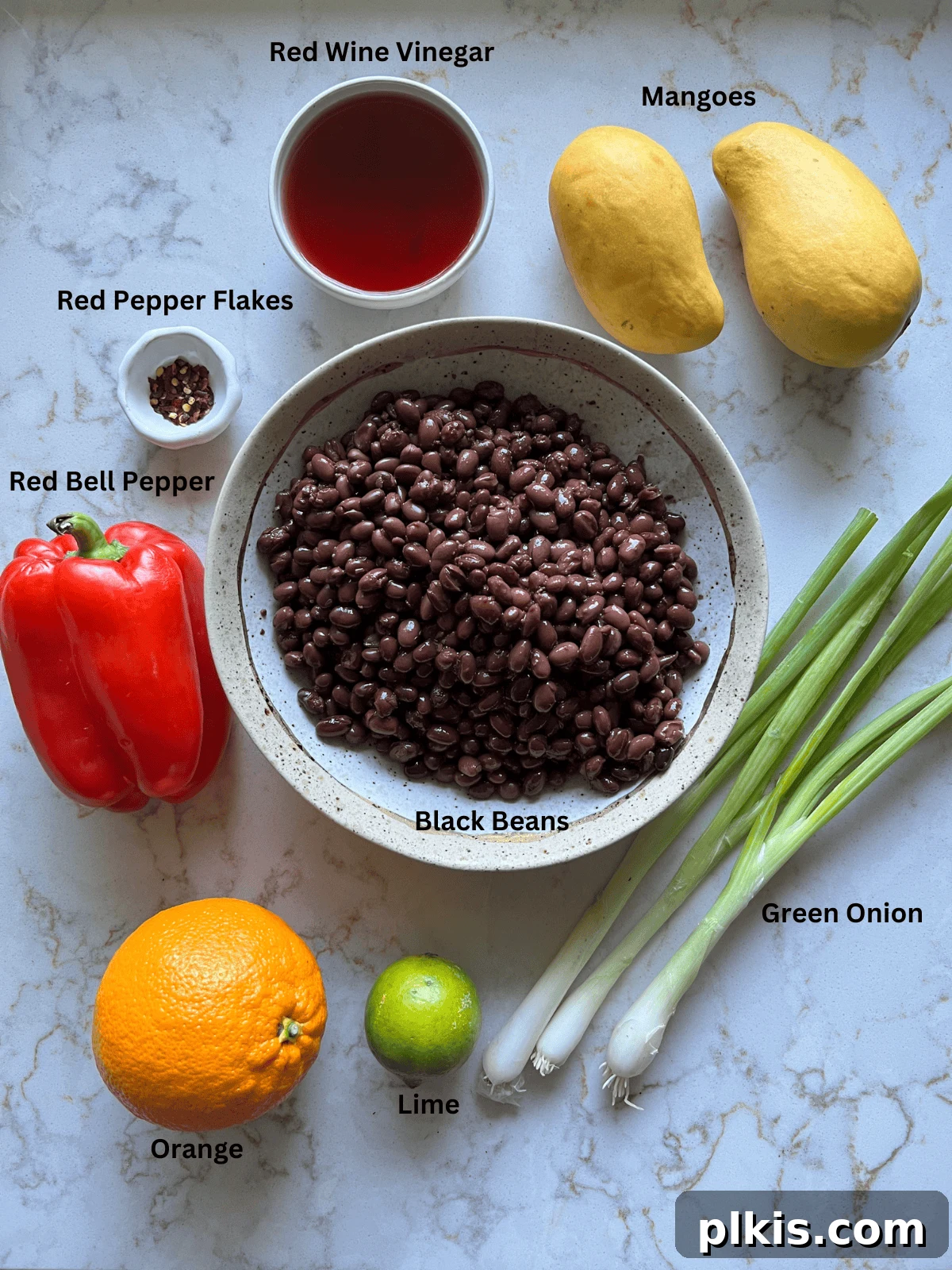 All the measured ingredients for mango black bean salad laid out neatly on a white surface, ready for preparation.