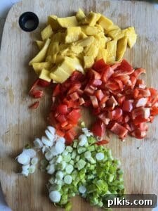 Freshly chopped bell pepper and other vegetables neatly arranged on a cutting board, ready for the mango black bean salad.