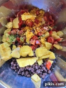 All the chopped ingredients for the Mango Black Bean Salad mixed together in a large bowl, showing a vibrant medley of colors.