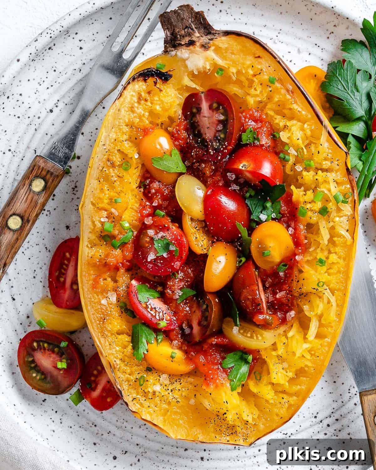 The Secret to Delicious Baked Spaghetti Squash 2 Golden brown roasted spaghetti squash halves ready to be flaked into pasta-like strands, presented beautifully on a white surface.