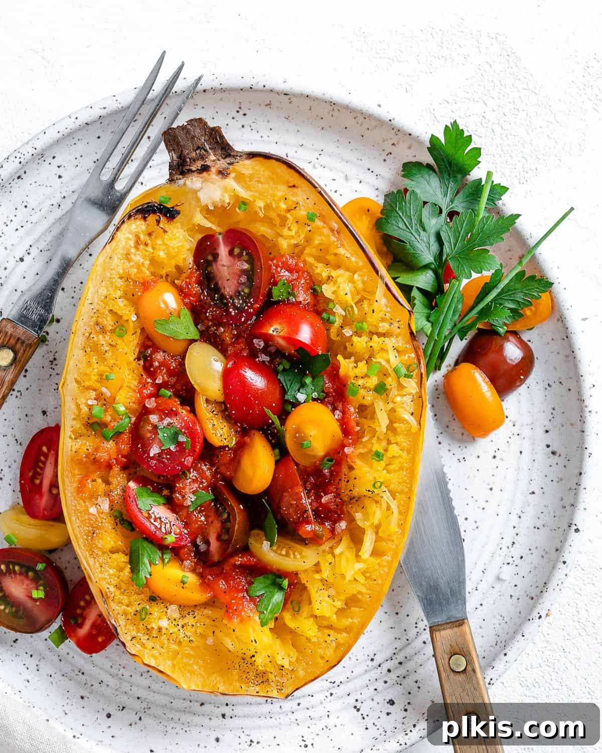 The Secret to Delicious Baked Spaghetti Squash 8 A fork pulling spaghetti-like strands from a roasted spaghetti squash half on a white plate, highlighting its unique texture.