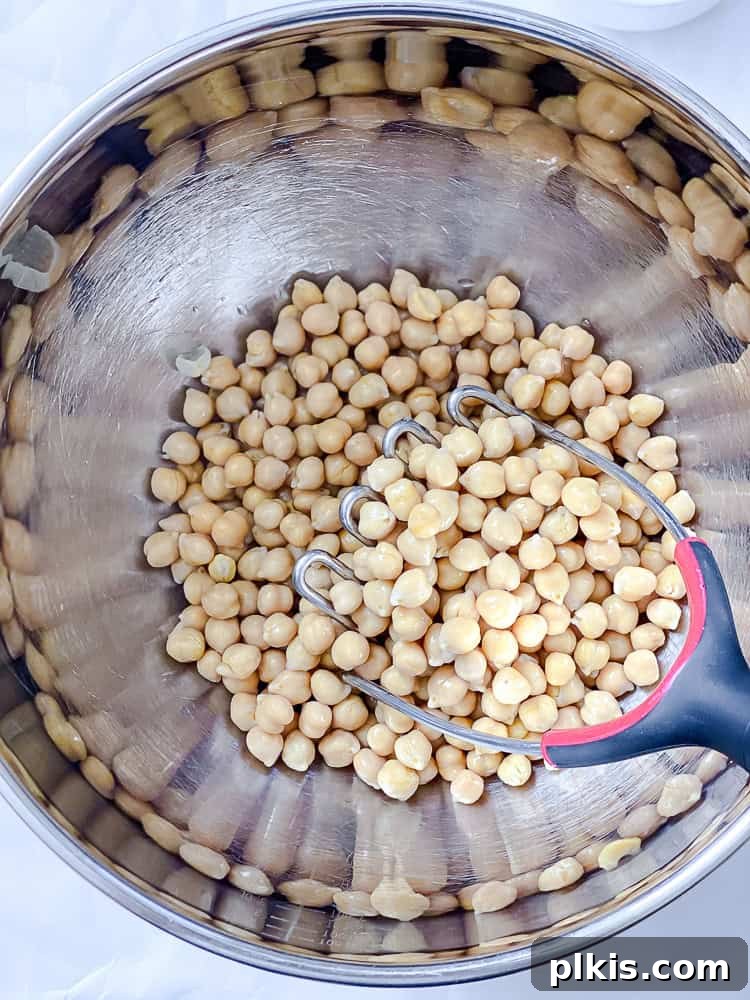 Vibrant Vegan Chickpea Salad 4 Process shot showing drained and rinsed chickpeas being added to a mixing bowl, ready for mashing.