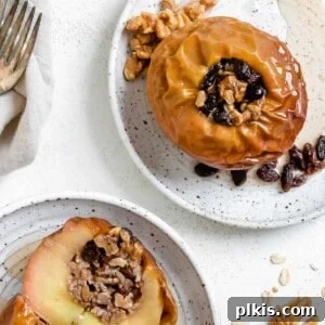 two completed plated stuffed baked apples on white plates against a white background