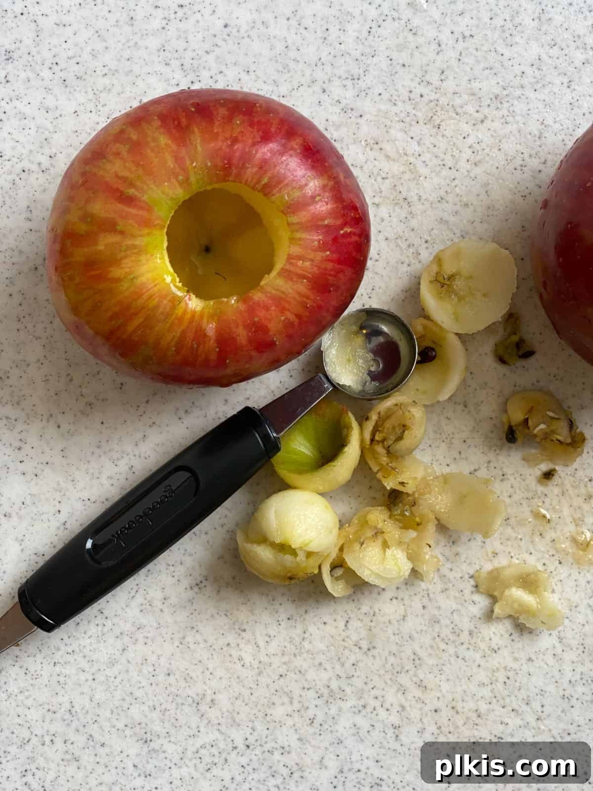 Baked Apple Delights 4 Process shot showing the process of using a melon baller to remove the stem and core of an apple, highlighting the cavity created.