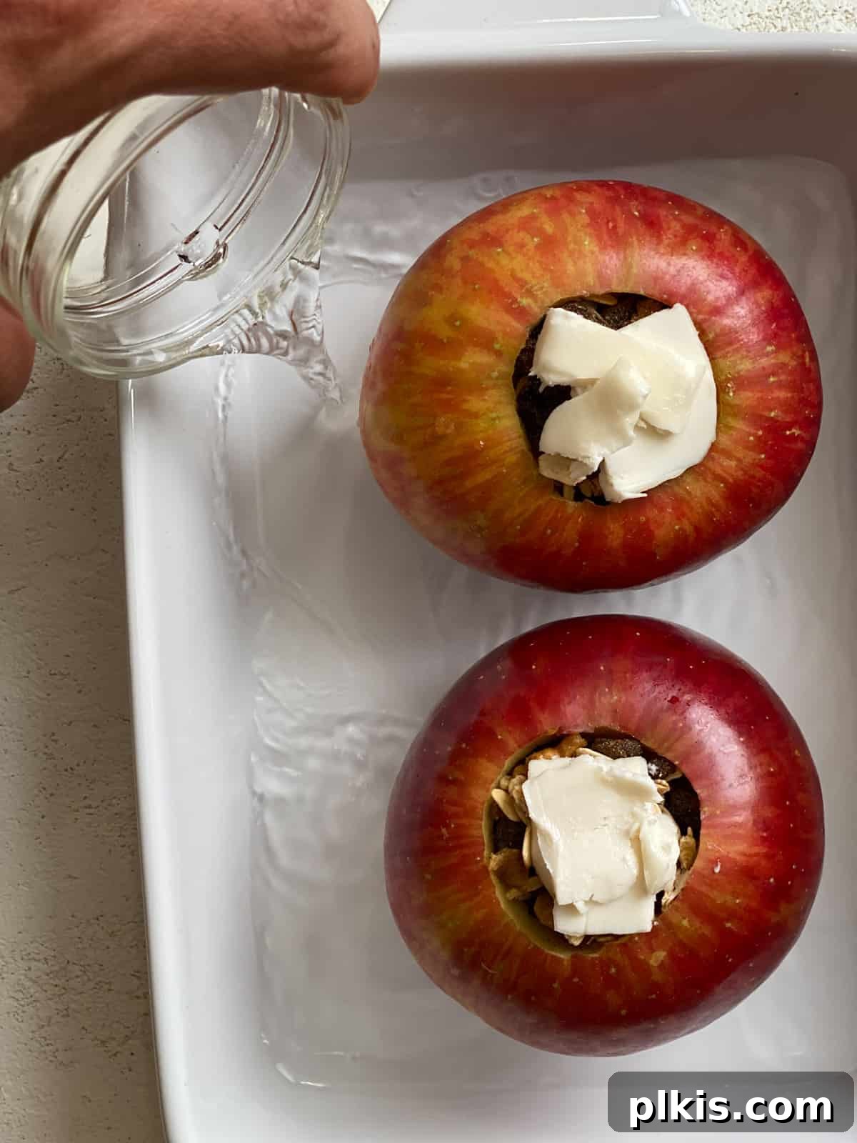 Baked Apple Delights 8 Process shot of adding water to a baking dish containing two stuffed apples.