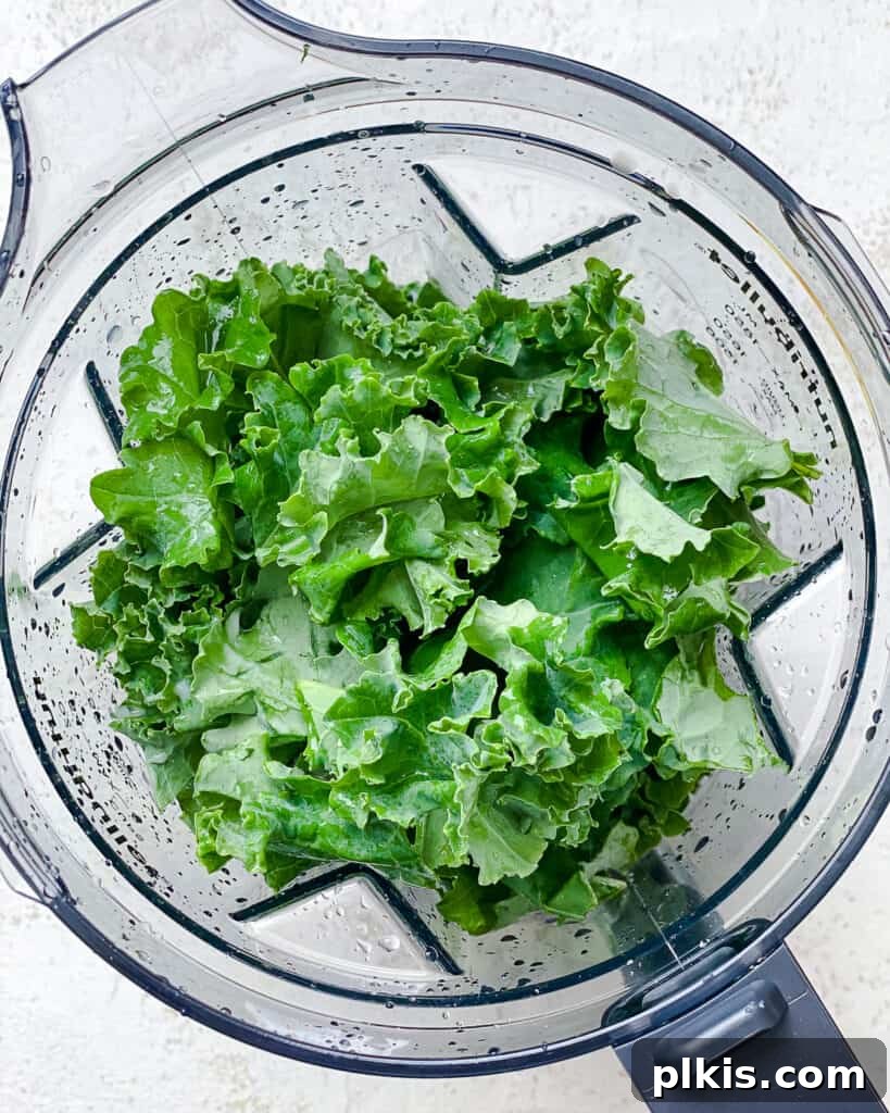 Emerald Pineapple Splash 5 Process shot of adding kale to blender with liquids.