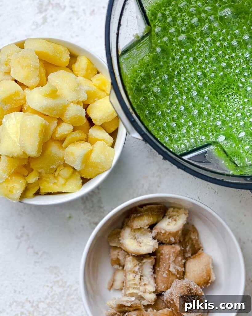 Emerald Pineapple Splash 6 Blended kale and liquids in blender alongside a bowl of frozen pineapple and banana.