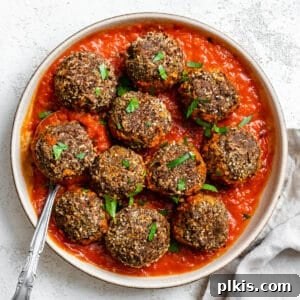 Completed Easy Black Bean Meatballs arranged on a plate with marinara sauce, garnished with fresh herbs