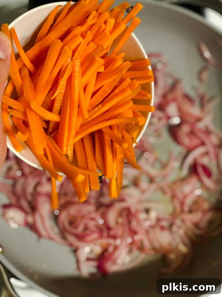 Vibrant Veggie Noodle Medley 6 process shot of carrots being addd to pan