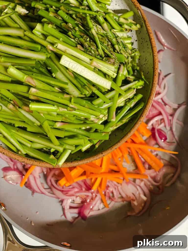 Vibrant Veggie Noodle Medley 7 process shot of asparagus being added to pan