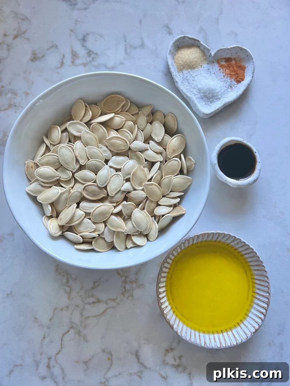 Fiery Roasted Pumpkin Seeds 3 Measured ingredients for spicy roasted pumpkin seeds, including pumpkin seeds, olive oil, soy sauce, garlic powder, and cayenne pepper, displayed on a white surface.