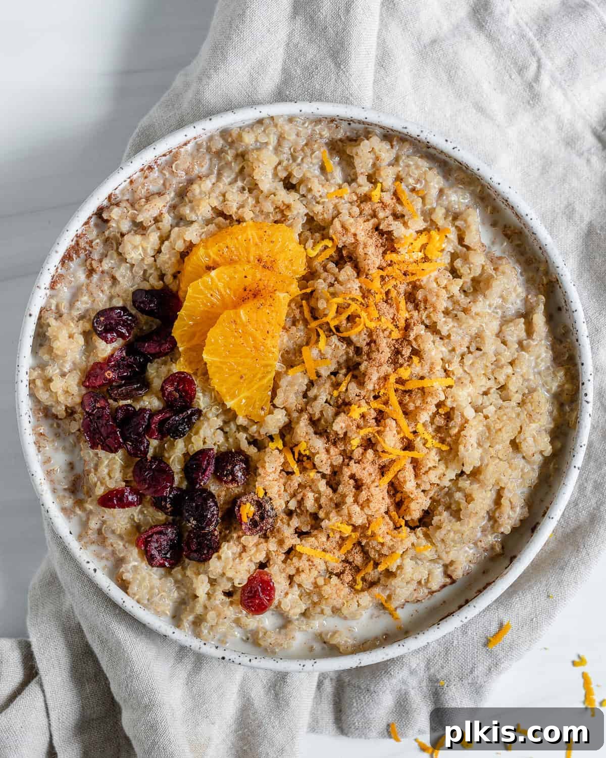Spiced Orange Quinoa 2 A beautifully presented bowl of Cinnamon Orange Quinoa porridge, garnished with orange zest and dried fruits, set against a light, inviting surface.