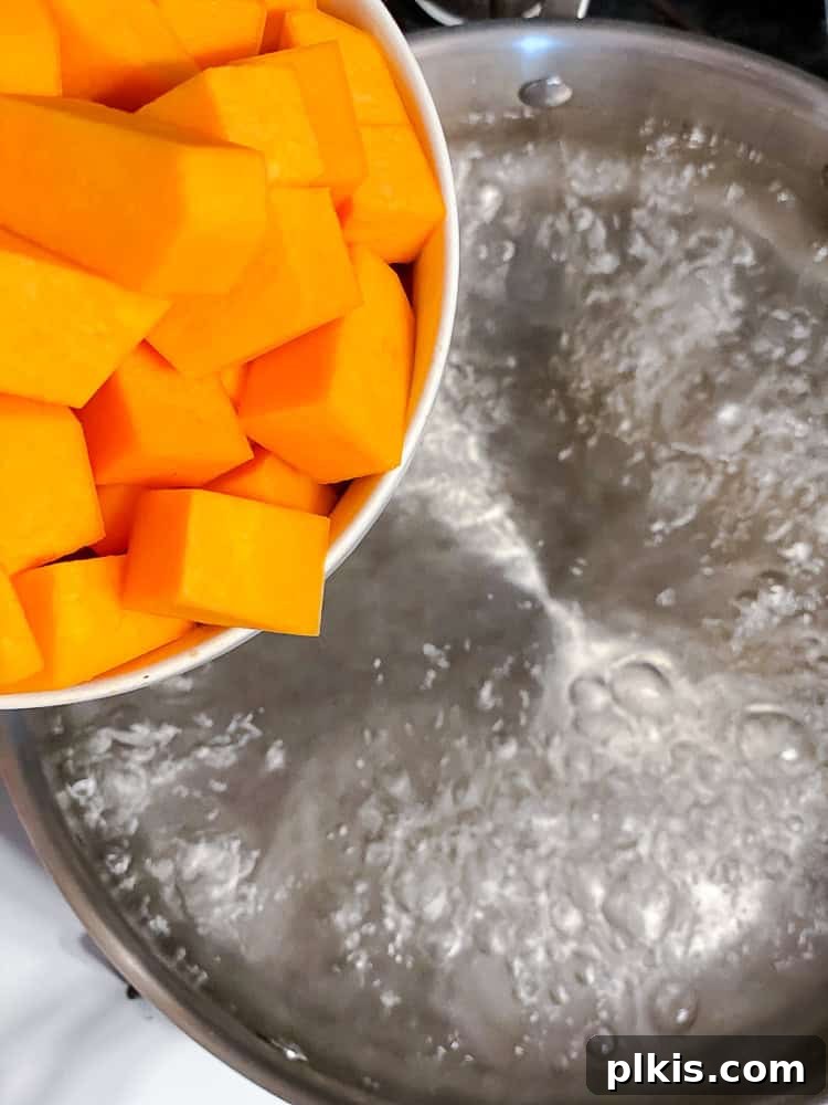 Golden Butternut Macaroni 4 Process shot showing adding cubed butternut squash to a pot of boiling water.