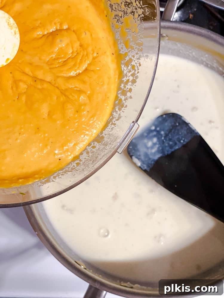 Golden Butternut Macaroni 7 Process shot showing the blended butternut squash mixture being added to the roux in a pan.