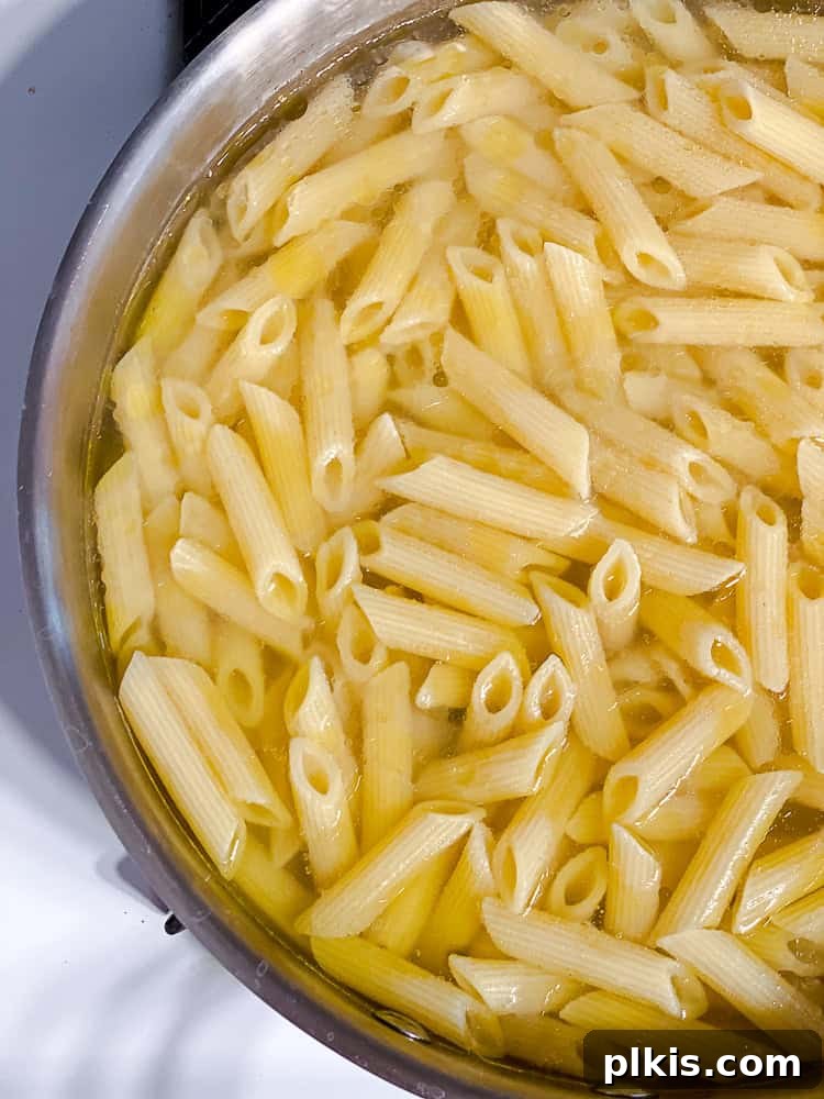 Vibrant Vegan Primavera Pasta 4 Pasta cooking in a pot of boiling water, steam rising.