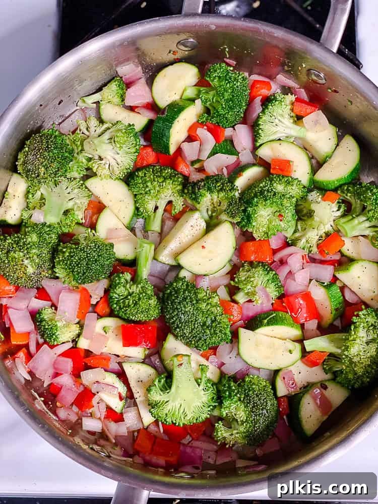 Vibrant Vegan Primavera Pasta 6 Broccoli and zucchini florets being stirred into sautéed vegetables in a large pot.
