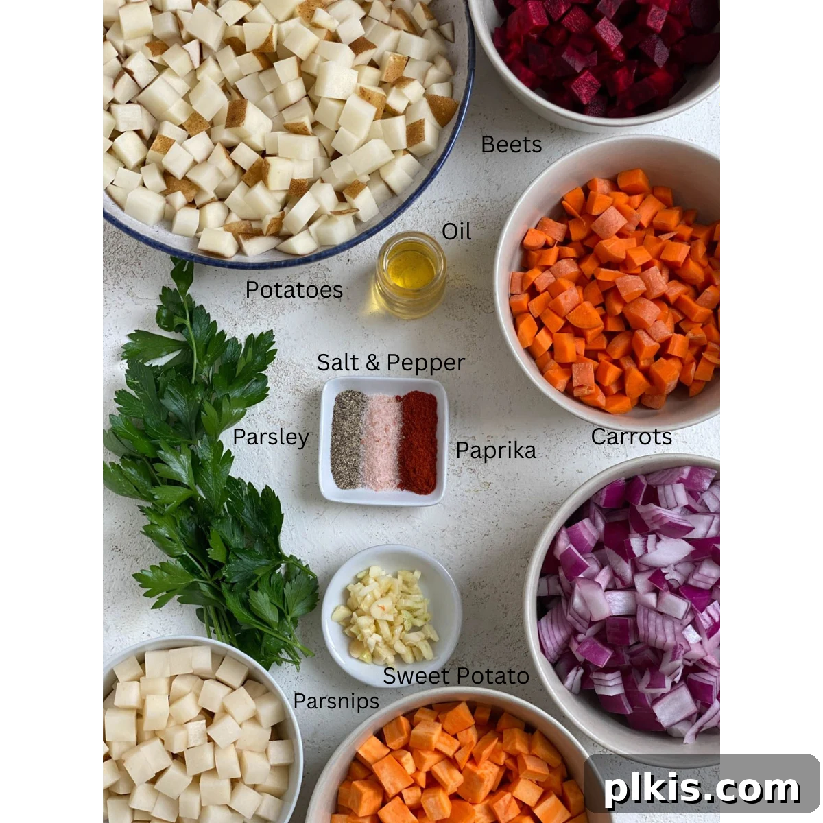 One-Pan Roasted Root Vegetable Medley 3 A selection of fresh, diced root vegetables and aromatics laid out on a white surface, ready for the One-Pan Root Vegetable Hash recipe.