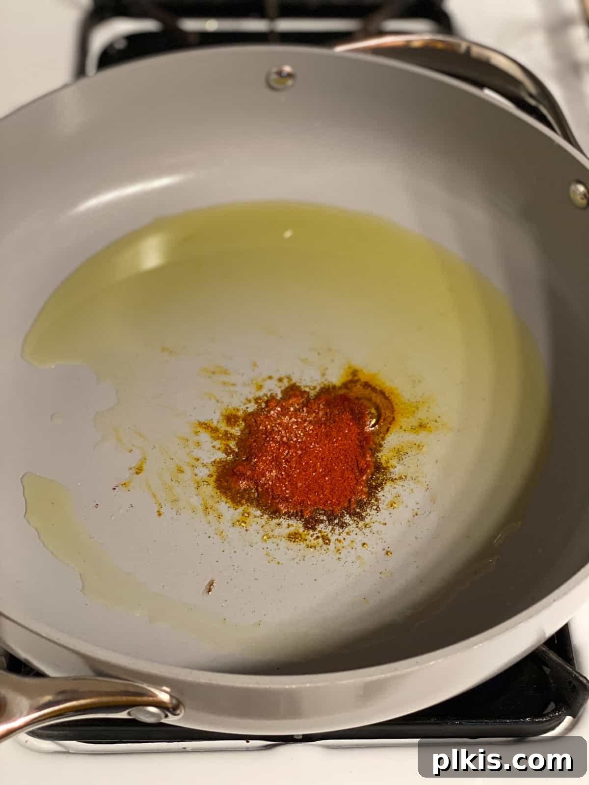 One-Pan Roasted Root Vegetable Medley 4 Process shot showing paprika being added to hot oil in a skillet, sizzling to release its flavor.