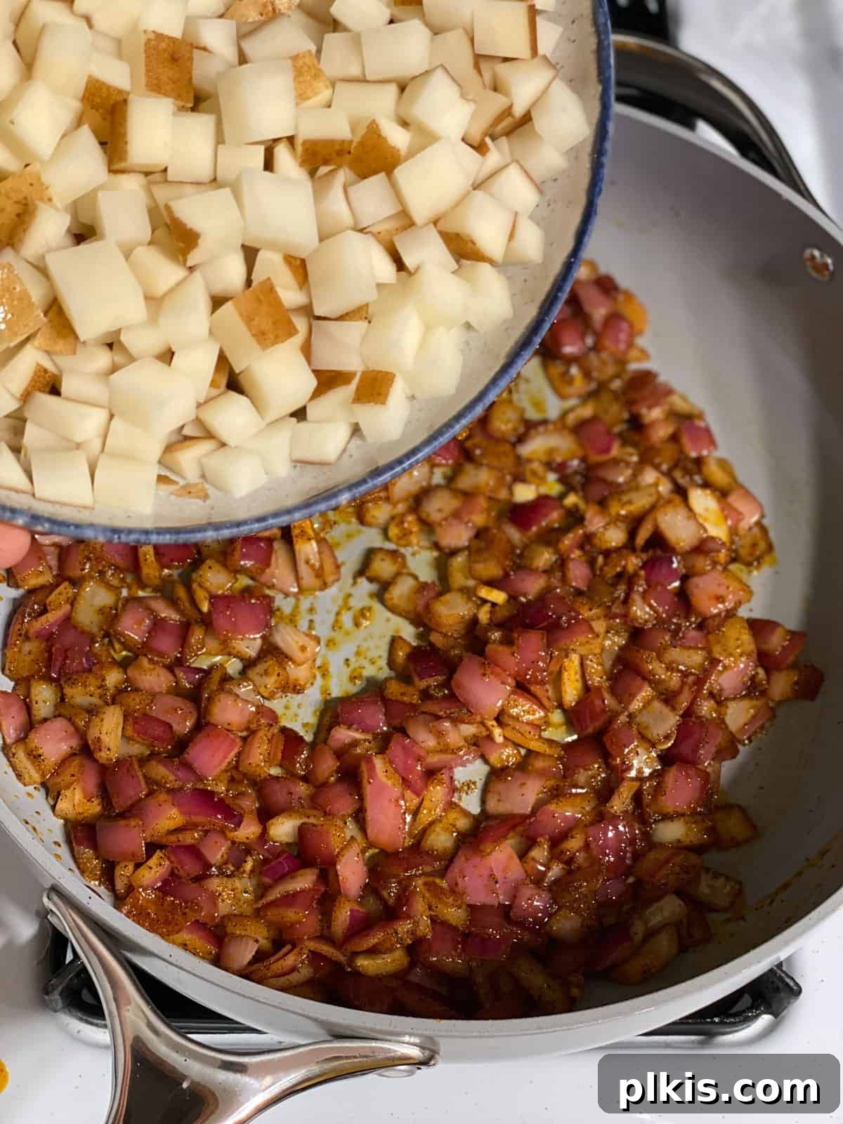 One-Pan Roasted Root Vegetable Medley 7 Process shot of diced potatoes being added to the skillet, starting the cooking process for the root vegetable hash.