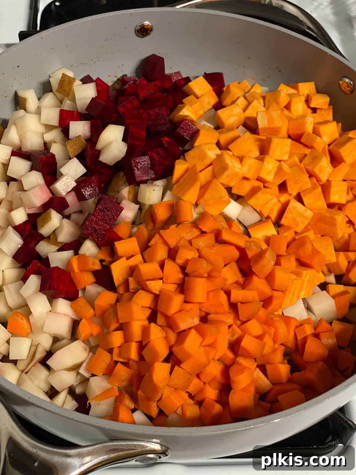 One-Pan Roasted Root Vegetable Medley 8 Process shot of a colorful mix of root vegetables, including beets, sweet potatoes, and carrots, added to the skillet.