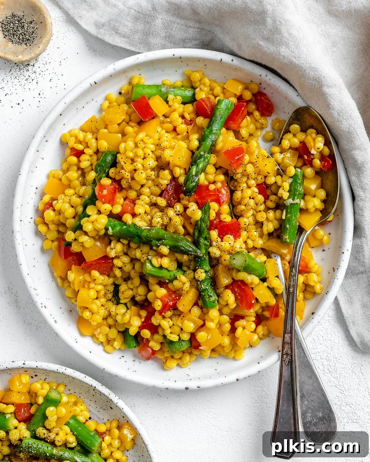 Vibrant Vegan Couscous with Fresh Vegetables 2 Completed Vegetable Couscous in a white plate against a white surface, garnished with fresh herbs