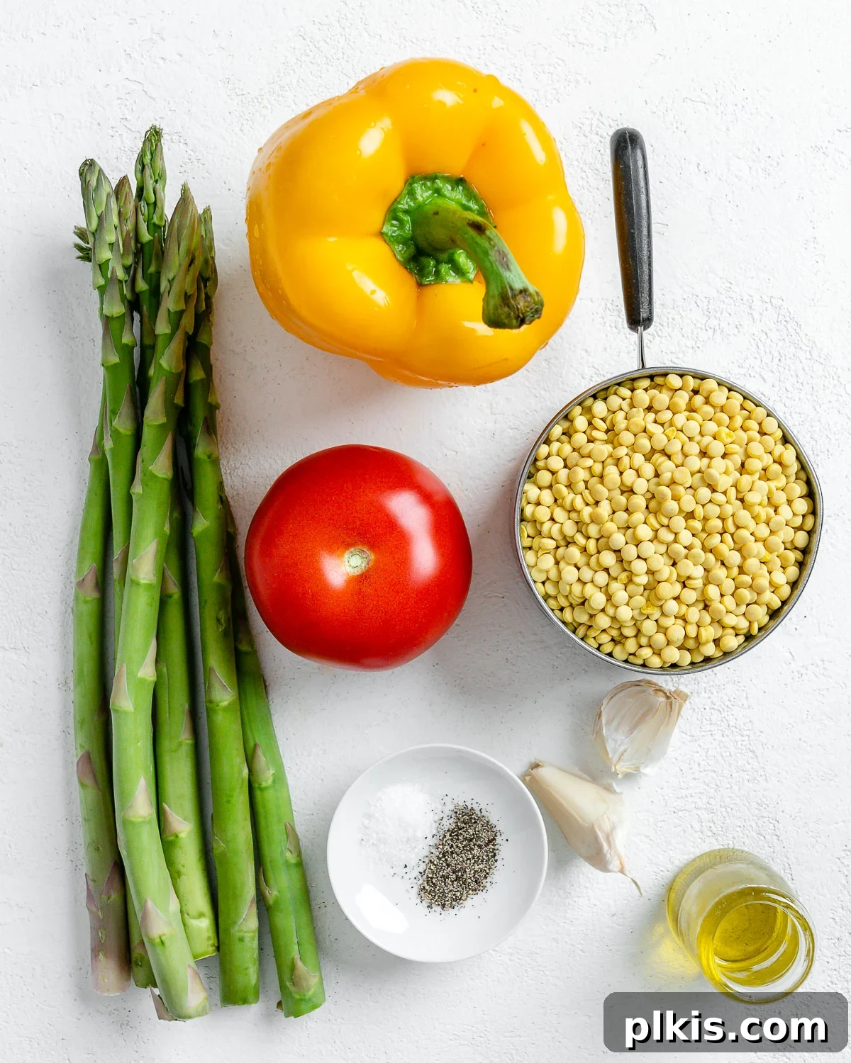 Vibrant Vegan Couscous with Fresh Vegetables 3 Ingredients for Vegetable Couscous laid out against a white surface, including dried couscous, oil, fresh asparagus, bell pepper, and tomato