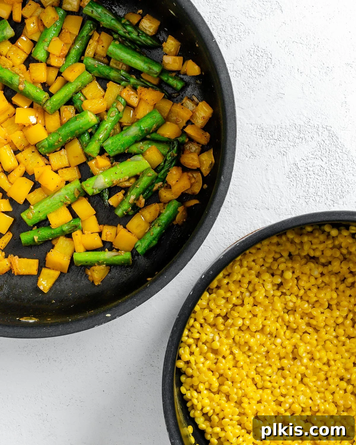 Vibrant Vegan Couscous with Fresh Vegetables 6 Cooked couscous alongside a pan of sautéed vegetables against a white surface, ready for combining