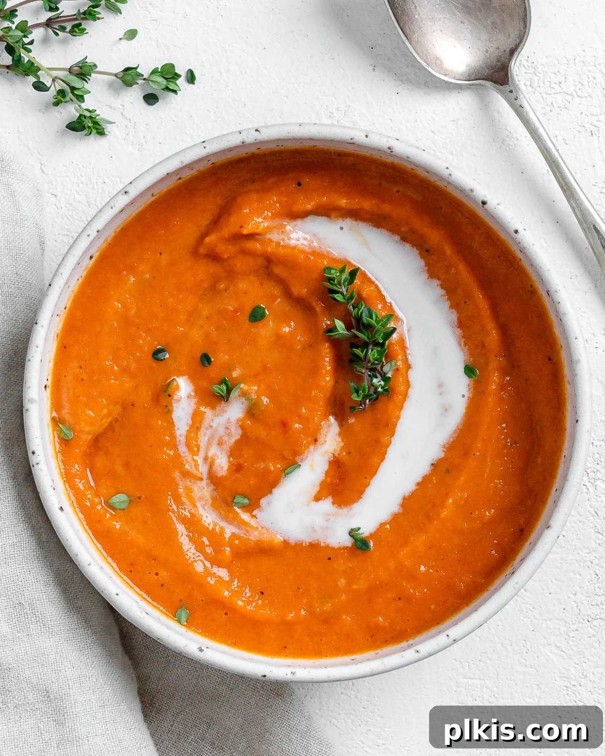 Velvety Vegan Tomato Thyme Bisque 2 Completed Vegan Tomato Bisque with Thyme in a white bowl against a light background.