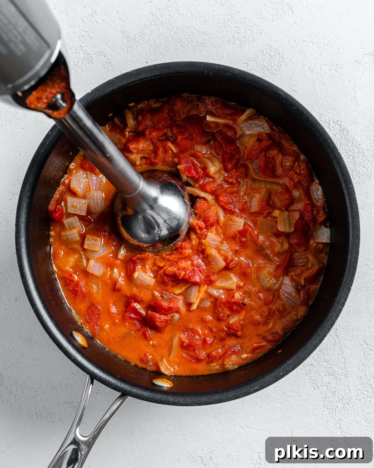 Velvety Vegan Tomato Thyme Bisque 6 Process shot of using immersion blender into black pan.