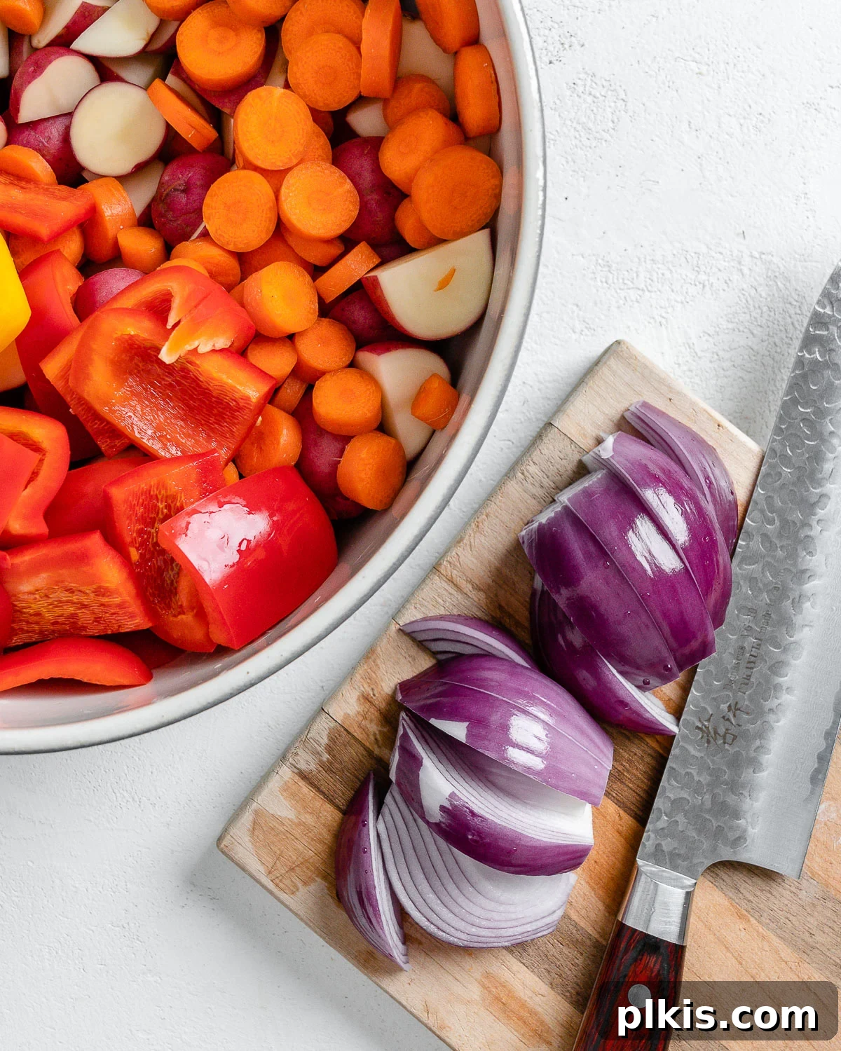 Thyme Kissed Roasted Vegan Medley 8 Sliced red onion on a cutting board, added to the bowl of mixed vegetables.
