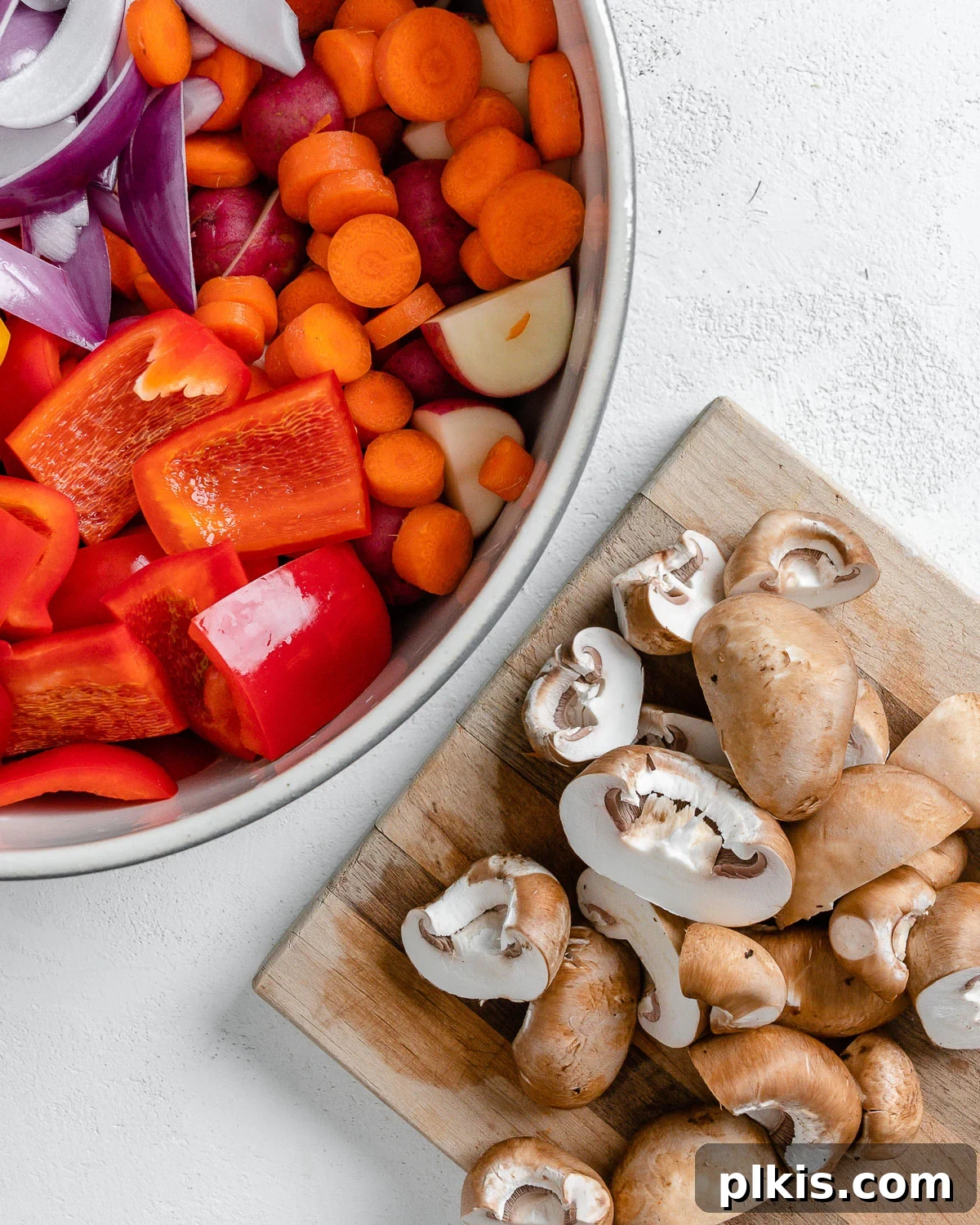 Thyme Kissed Roasted Vegan Medley 9 Chopped fresh mushrooms on a cutting board, alongside the bowl of other prepped vegetables.