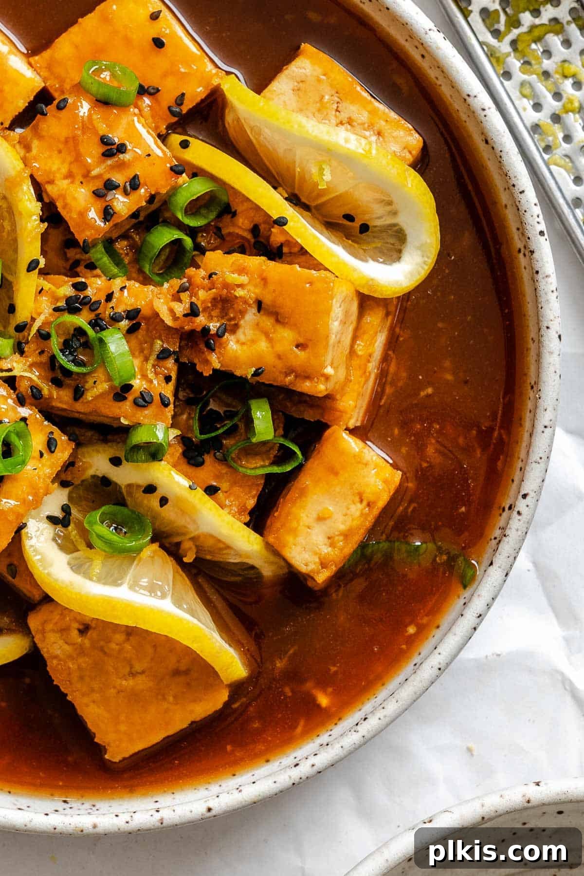 Zesty Lemon Glazed Tofu 2 Crispy sticky lemon tofu, coated in a glistening lemon sauce, served in a bowl.