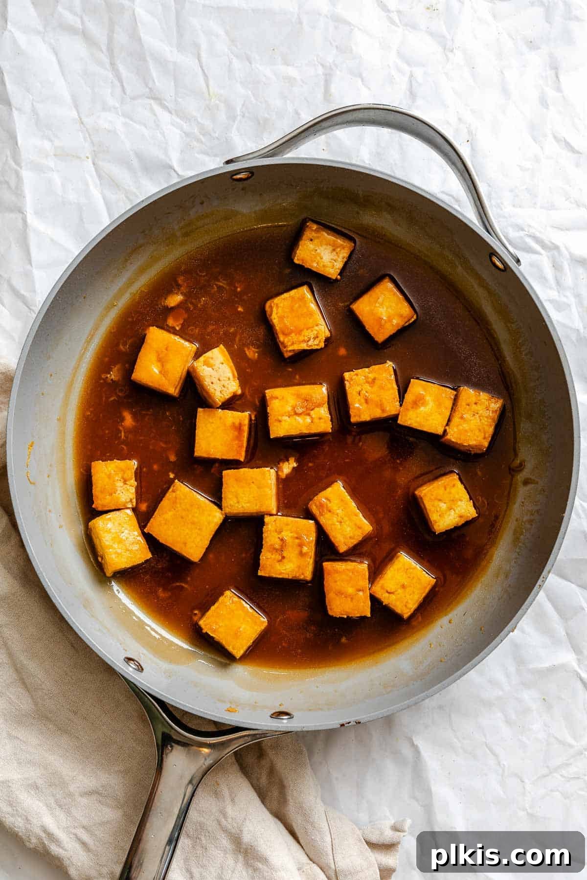 Zesty Lemon Glazed Tofu 6 Process shot showing lemon sauce being poured over crispy tofu in a pan.