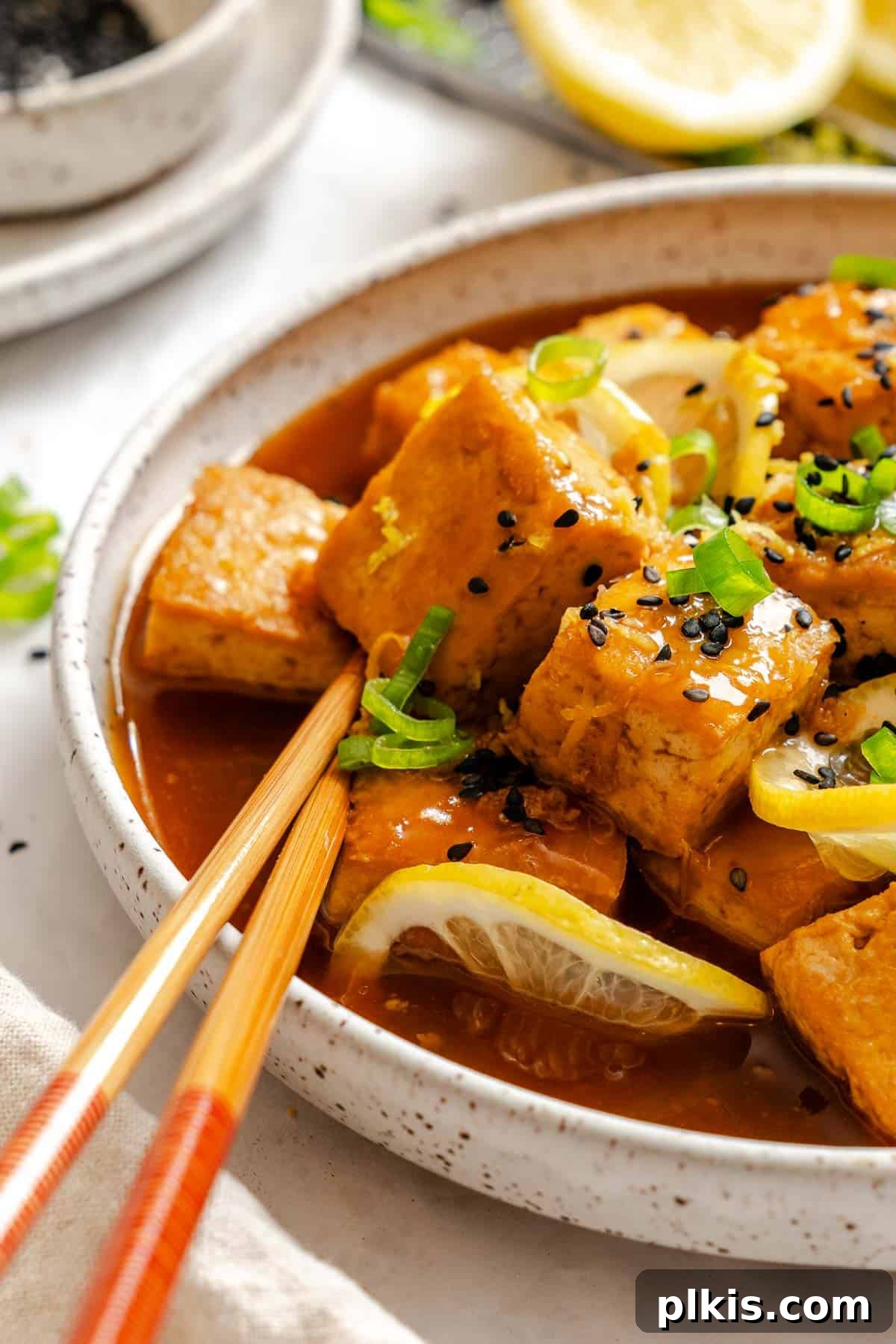 Zesty Lemon Glazed Tofu 7 Close-up of sticky lemon tofu coated in sauce, garnished with green onions.